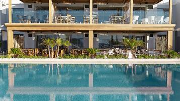A modern hotel with a pool, outdoor seating, and a two-story structure.