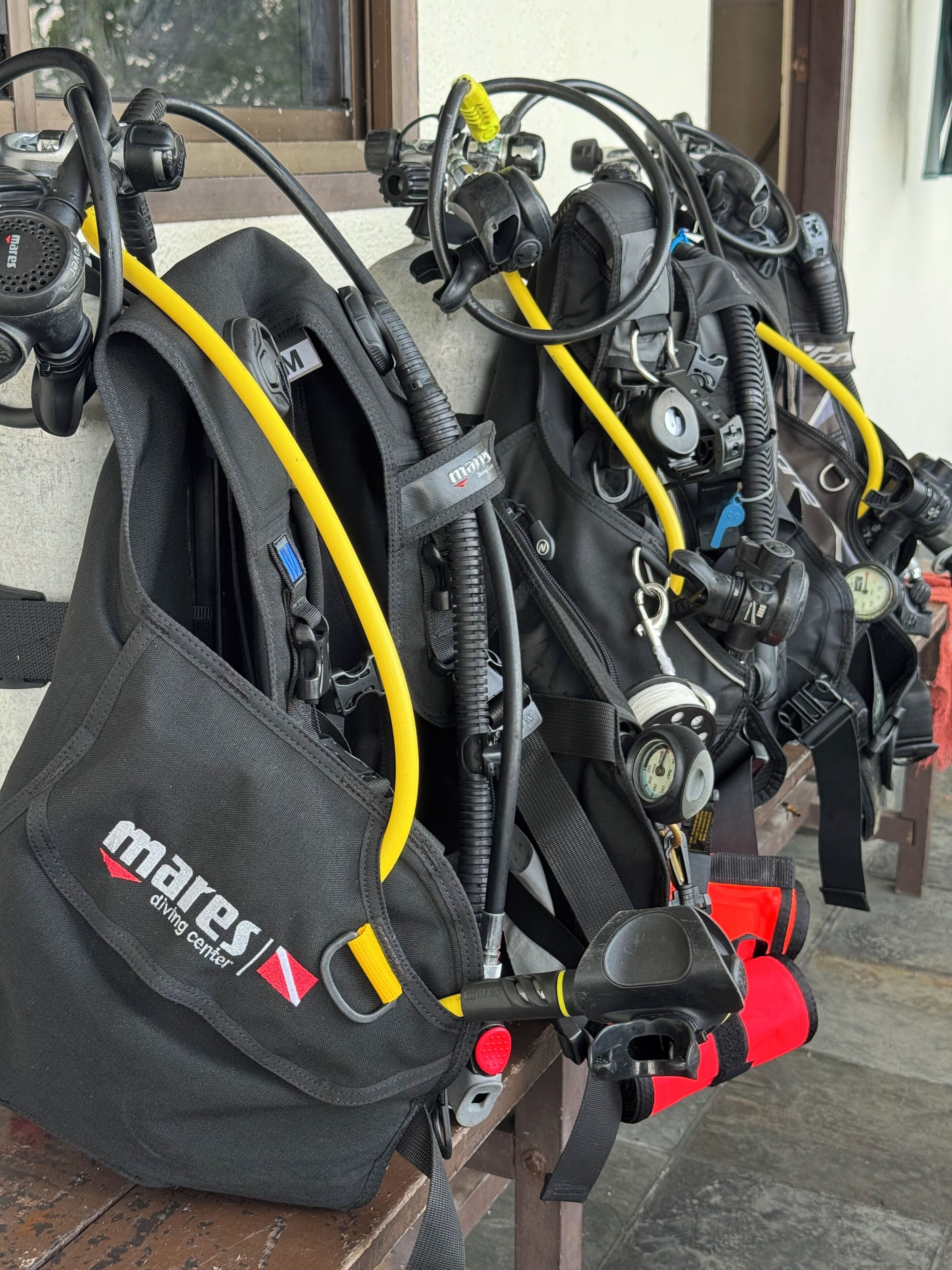 A row of diving gear with 'Mares Diving Center' branding, connected hoses, and a pressure gauge.