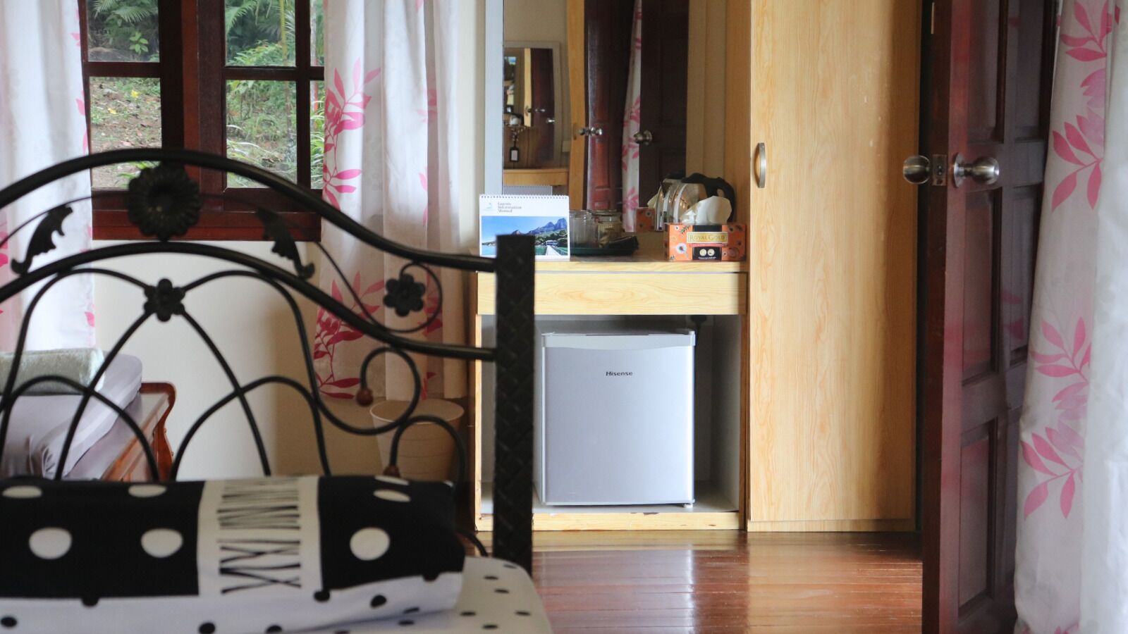 A room with a bed, a small refrigerator, and a wooden cabinet.