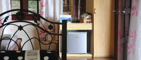 A room with a bed, a small refrigerator, and a wooden cabinet.
