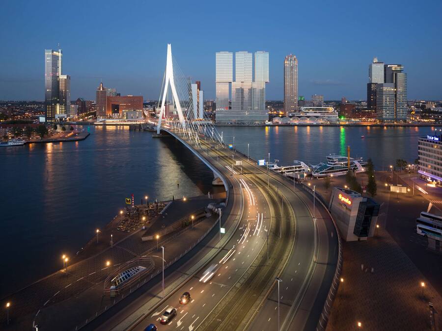 A modern cityscape with a prominent cable-stayed bridge, high-rise buildings, and a busy highway.