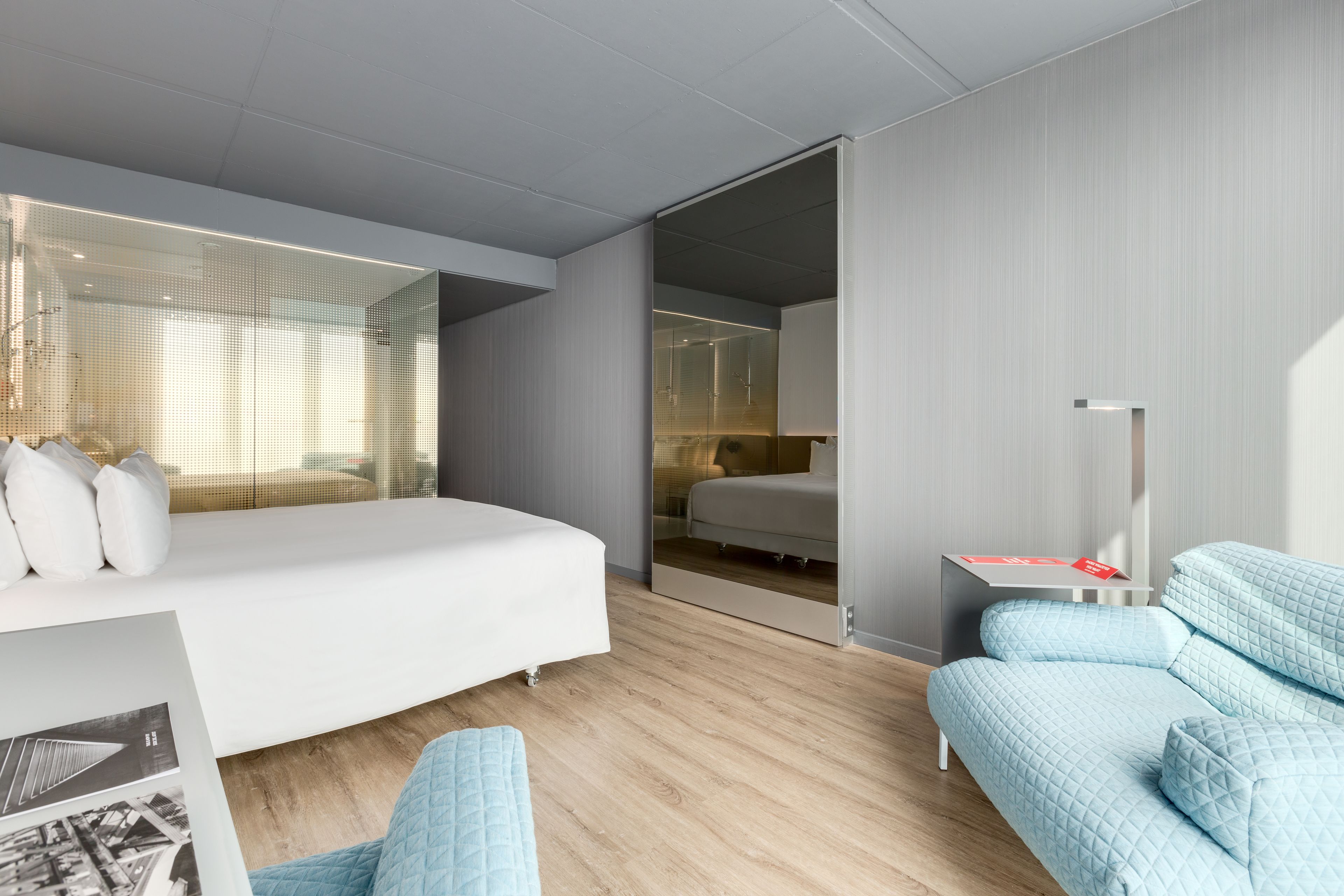 A modern hotel room with a large bed, a seating area with a sofa, and a small table.