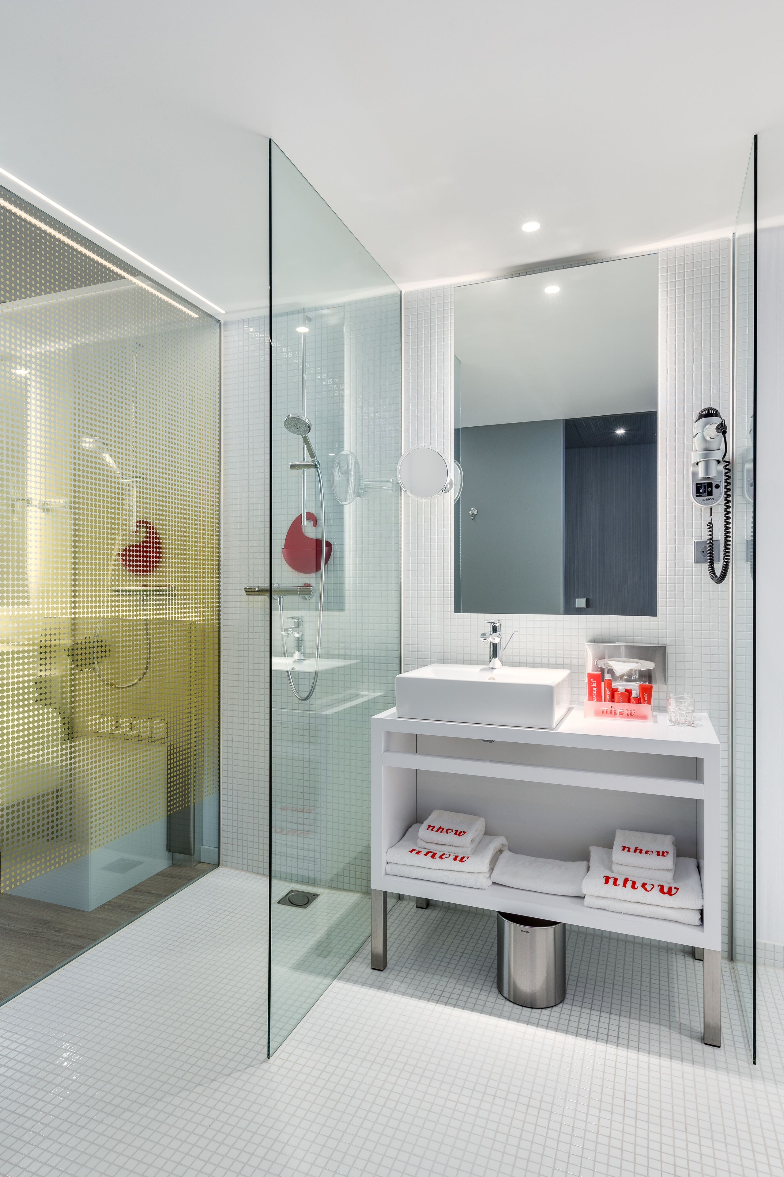A modern bathroom with a glass shower enclosure, a white sink, and a mirror above it.