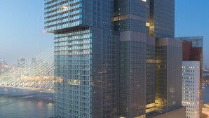 A modern skyscraper with a glass facade, located near a waterfront. - nhow Rotterdam Hotel (Rotterdam)