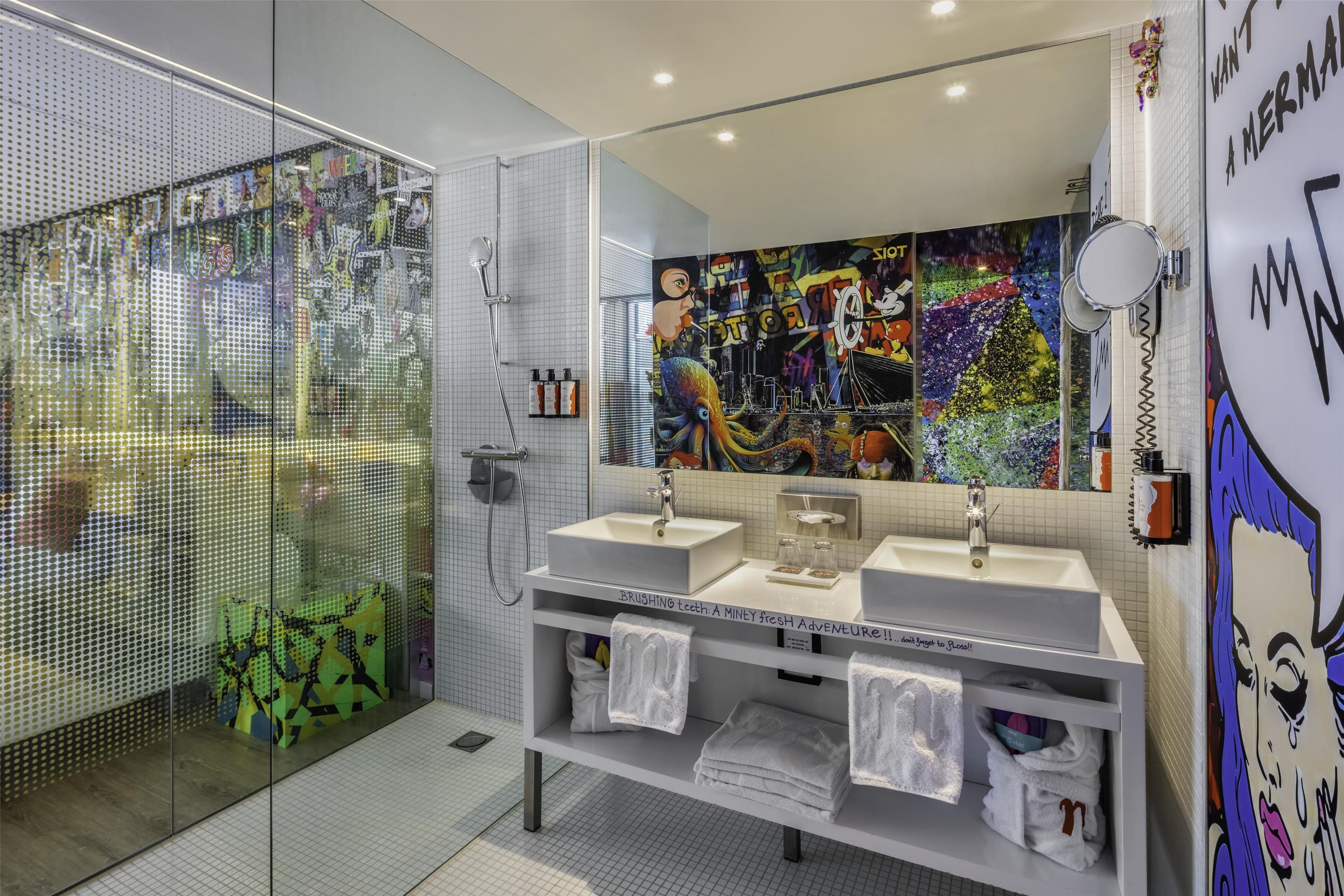 A modern bathroom with a glass shower enclosure, two sinks, and a large mirror.
