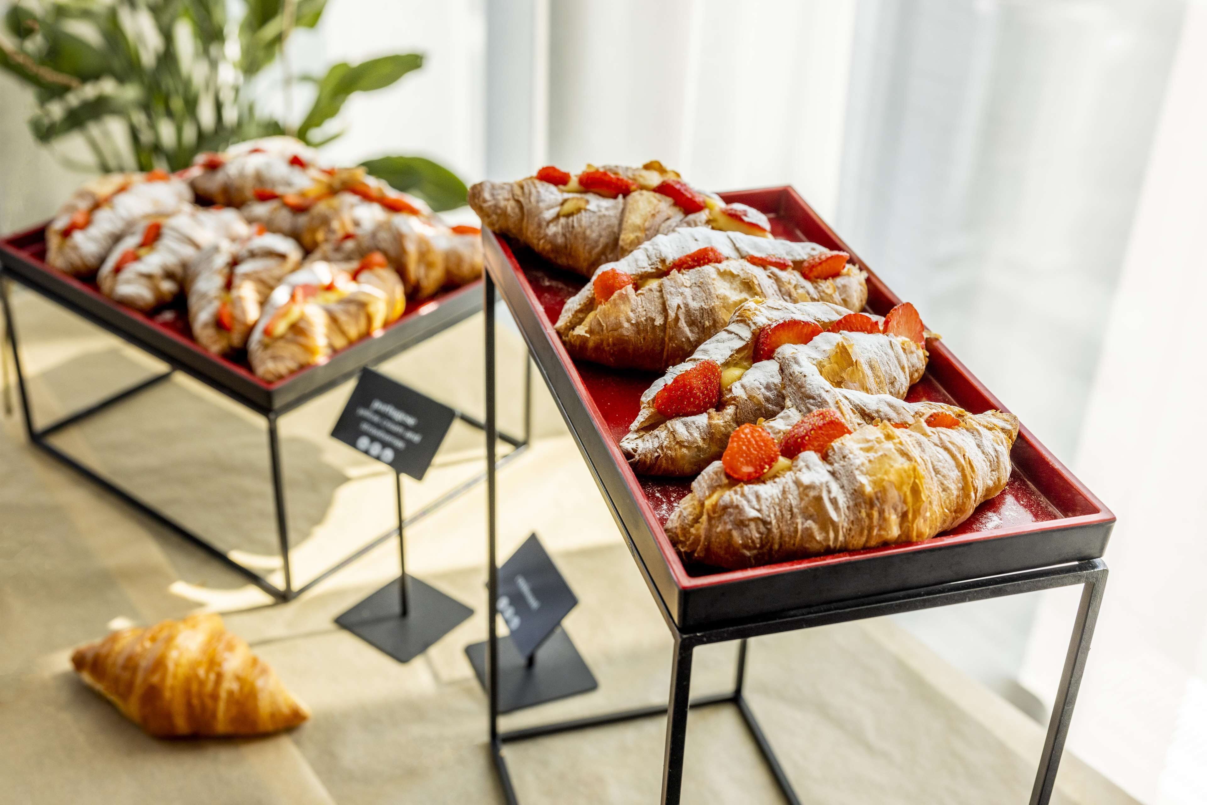 Des plateaux de pâtisseries aux fraises, saupoudrées de sucre glace, sont posés sur une table.