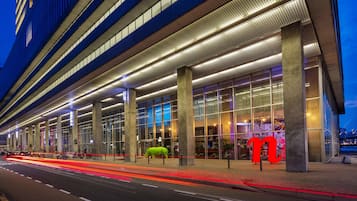 A modern hotel with a glass facade, large columns, and a prominent 'M' sign.