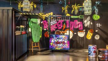 Un interior de restaurante vibrante con un letrero de neón, plantas colgantes y un mural colorido.