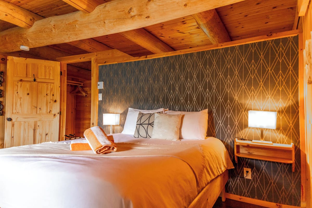 Ein schlicht eingerichtetes Schlafzimmer im Chalet-Stil mit einem Bett, zwei Nachttischen und einem Kleiderschrank.