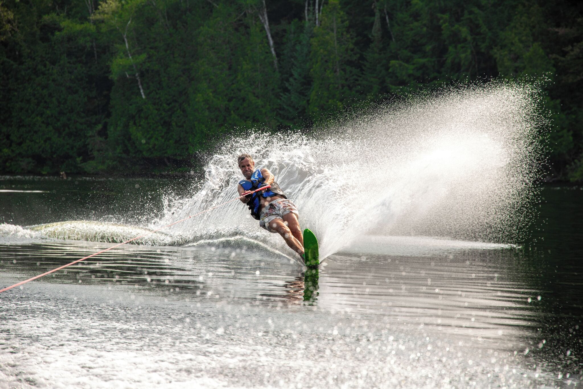 A person water skiing on a lake with trees in the background.