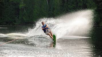 A person water skiing on a lake with trees in the background.
