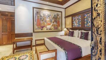 A hotel room with a large bed, a wooden bench, a desk, and a large painting on the wall.