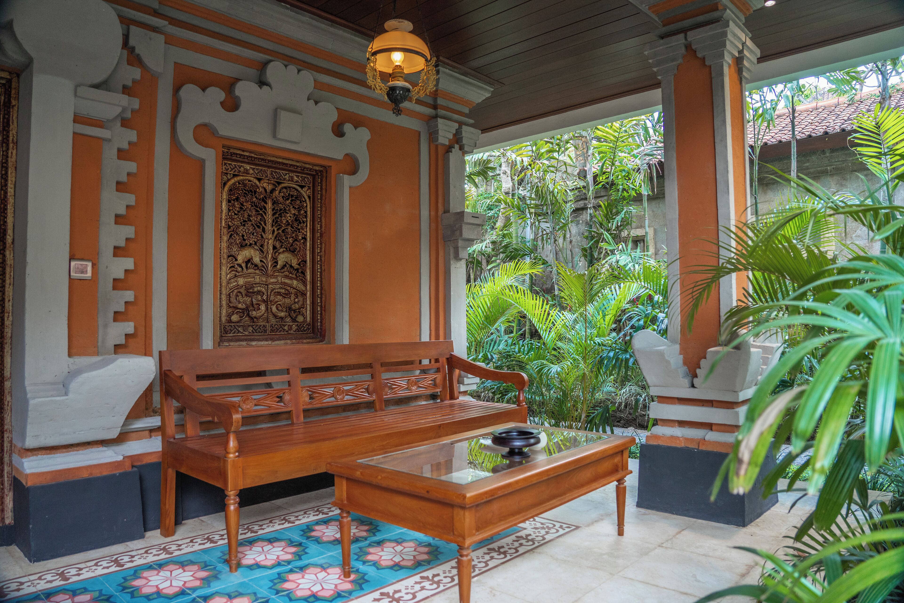 A traditional wooden bench and table set on a patterned floor, with a decorative door and columns in the background.