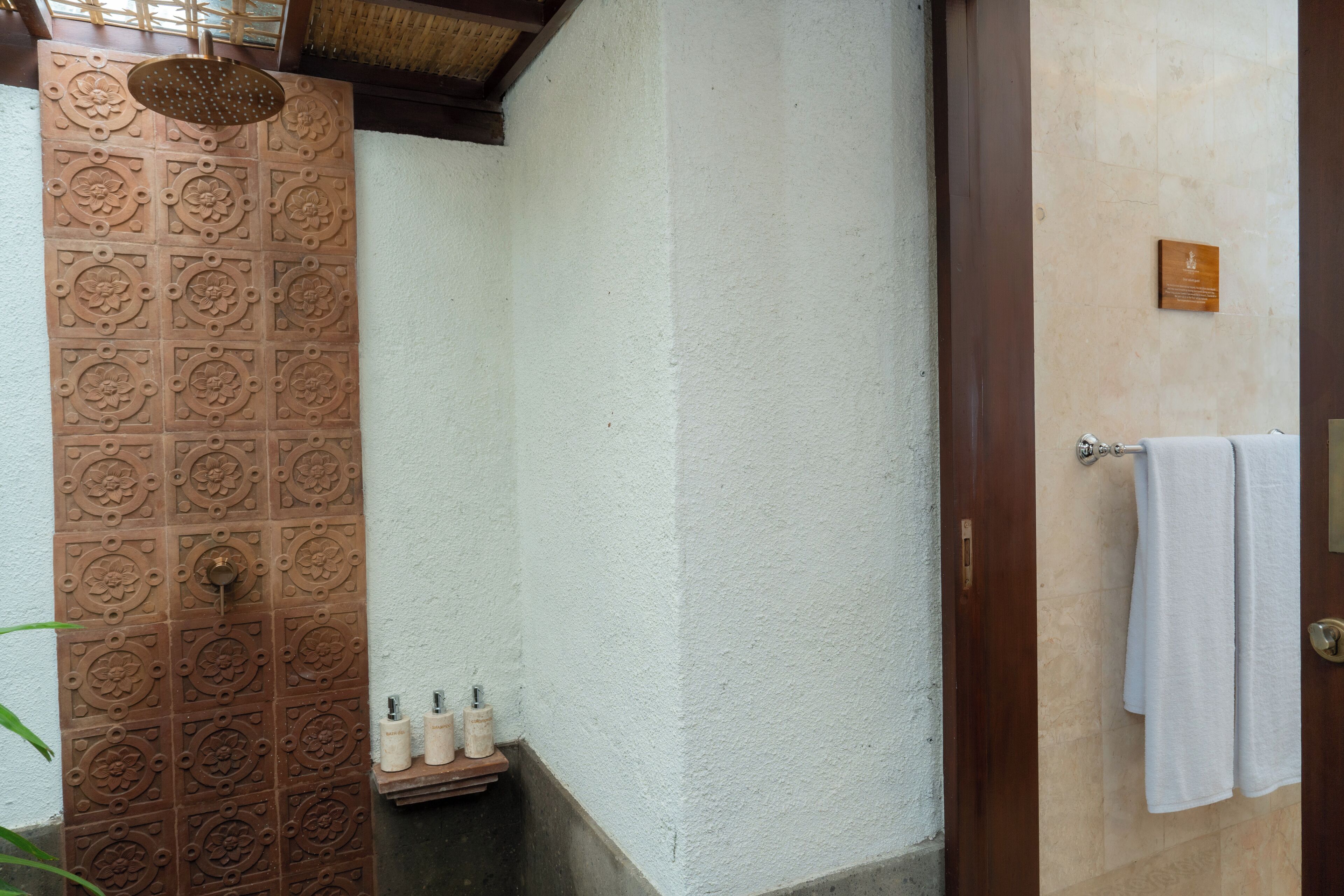 Un bagno con doccia in ceramica, un portasciugamani e un piccolo ripiano con articoli da toilette.