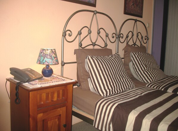 A bedroom with a metal bed frame, two striped pillows, a bedside table with a lamp, and a telephone. - B&B Het Wit Beertje (Bruges)