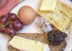 A plate with a variety of foods including grapes, a boiled egg, cheese, bread, and nuts. - Zazie Hôtel (Paris)