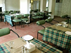 A dining area with multiple tables and chairs, some covered with checkered tablecloths. - Sunrise Hill Resort (Mawal)