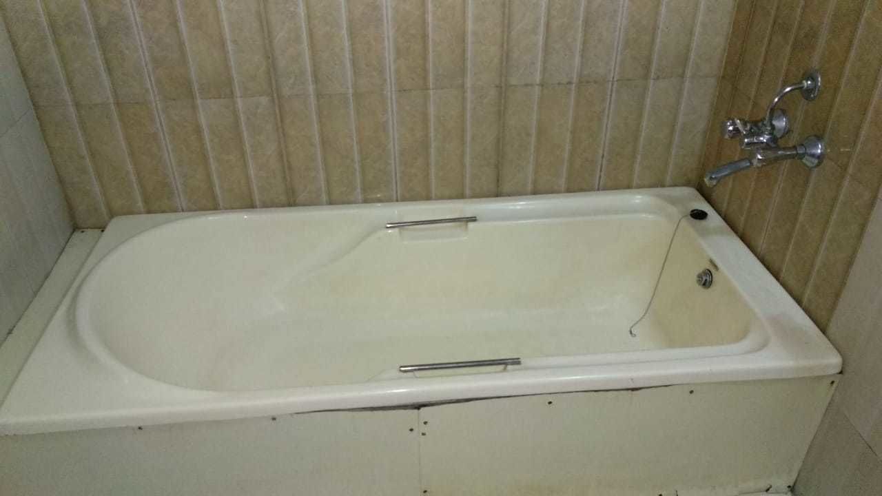 A rectangular bathtub with a chrome faucet and a single lever handle.