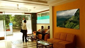 Hall dell'hotel con reception, area salotto e un'ampia finestra vista su spazi verdi.