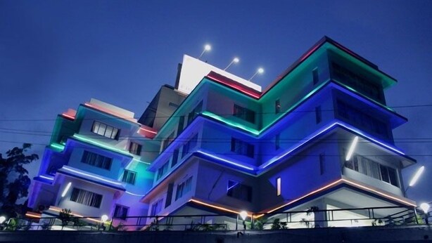 Un edificio residenziale a più piani con architettura moderna e illuminazione esterna colorata.