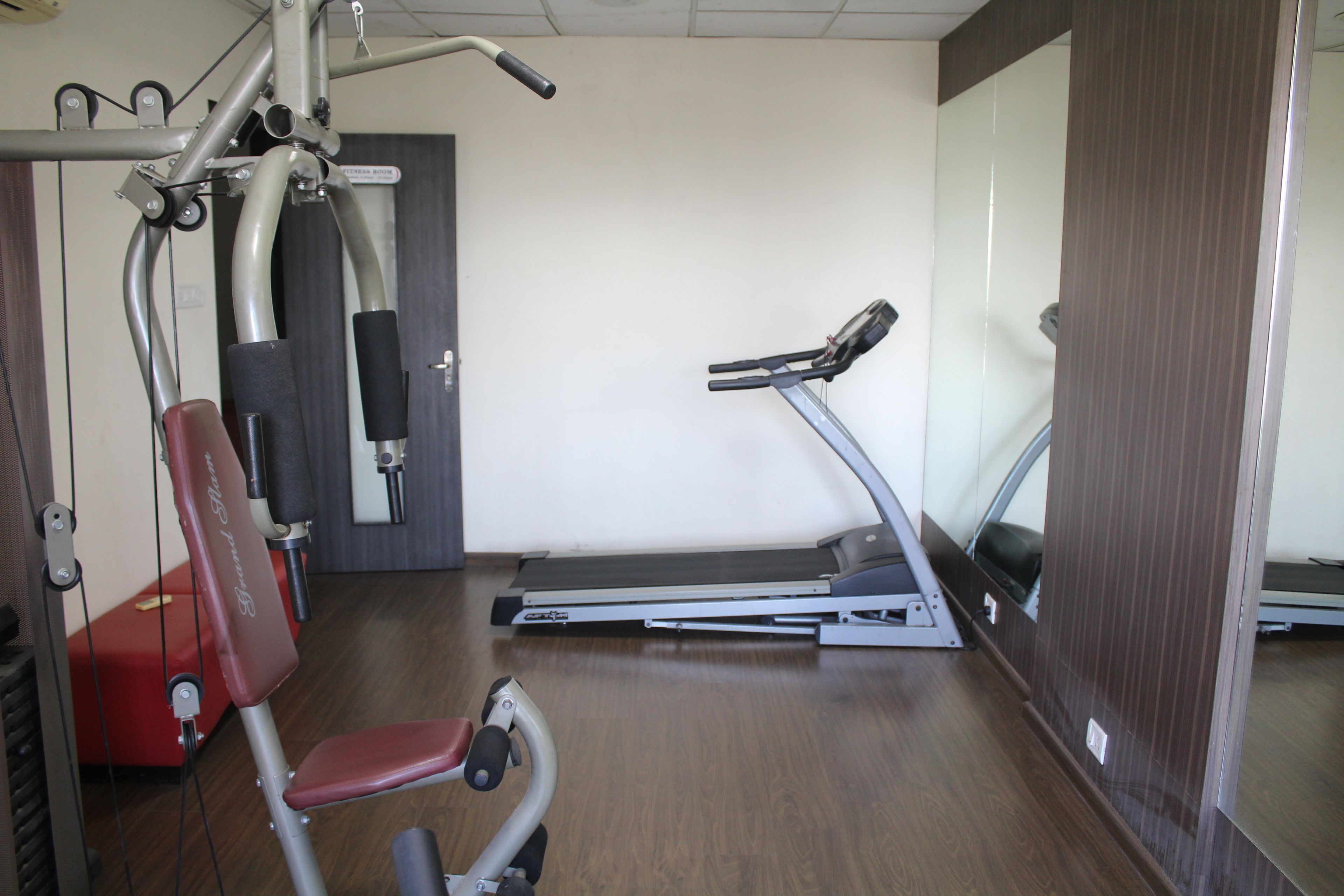 Un gimnasio con equipo de ejercicio, incluyendo una cinta de correr, bicicleta estática y máquinas de pesas.