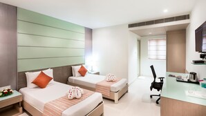 Ein Hotelzimmer mit zwei Betten, einem Schreibtisch und einem Stuhl.