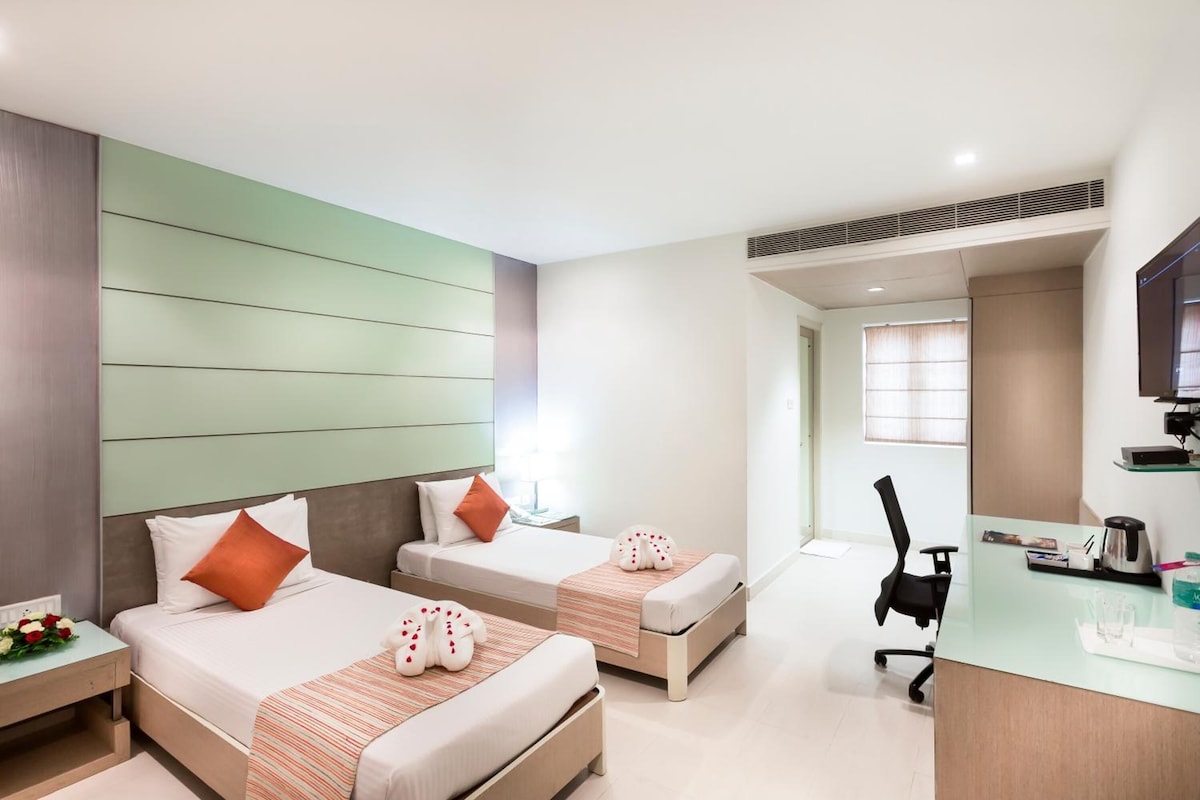 Une chambre d’hôtel avec deux lits, un bureau et une chaise.