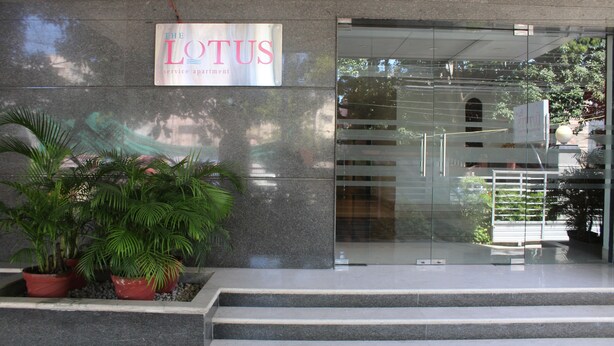 Ein Gebäudeeingang mit einem Schild, auf dem 'The Lotus Service Apartment' steht.