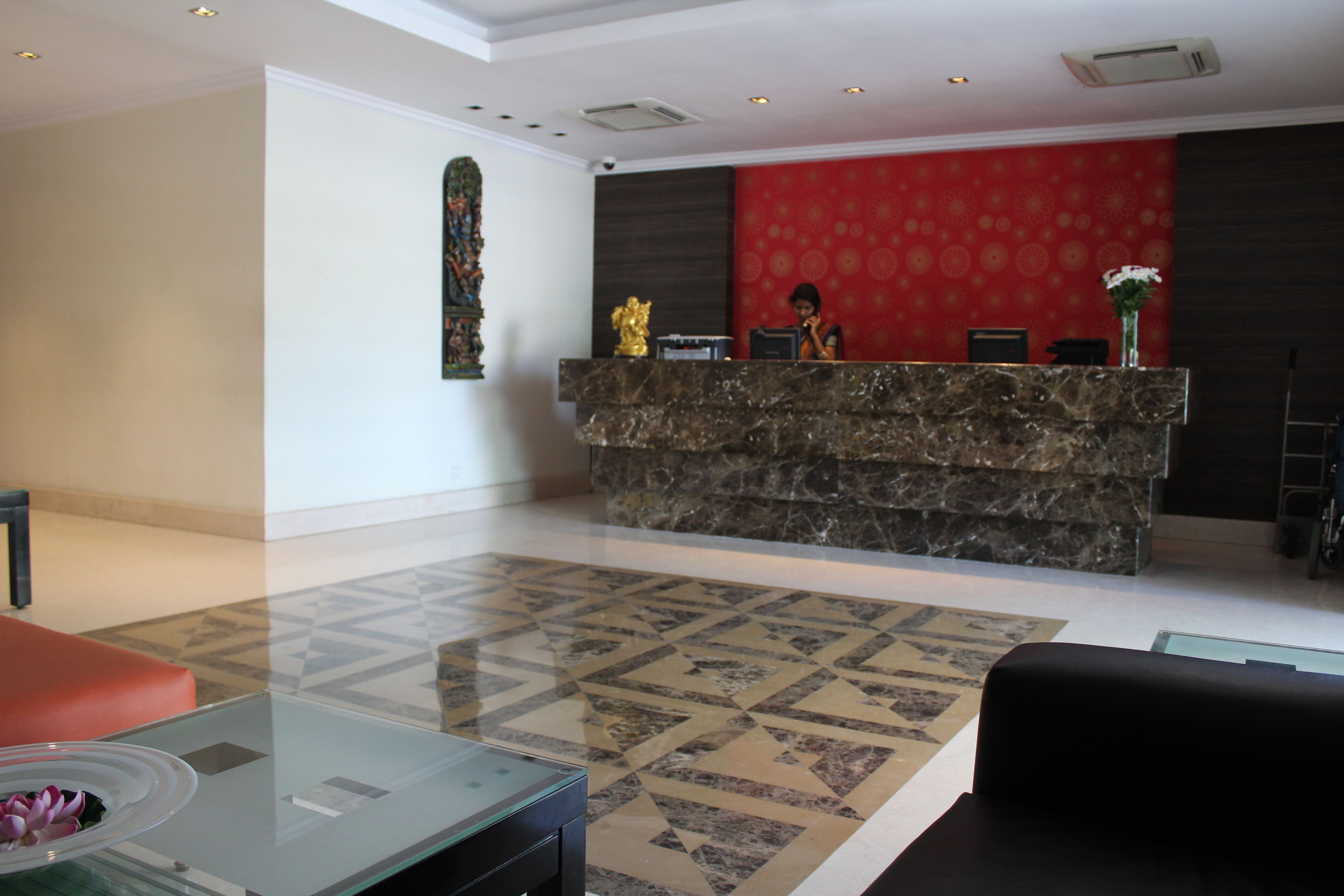 A reception area with a marble counter, a red patterned wall, and a tiled floor.