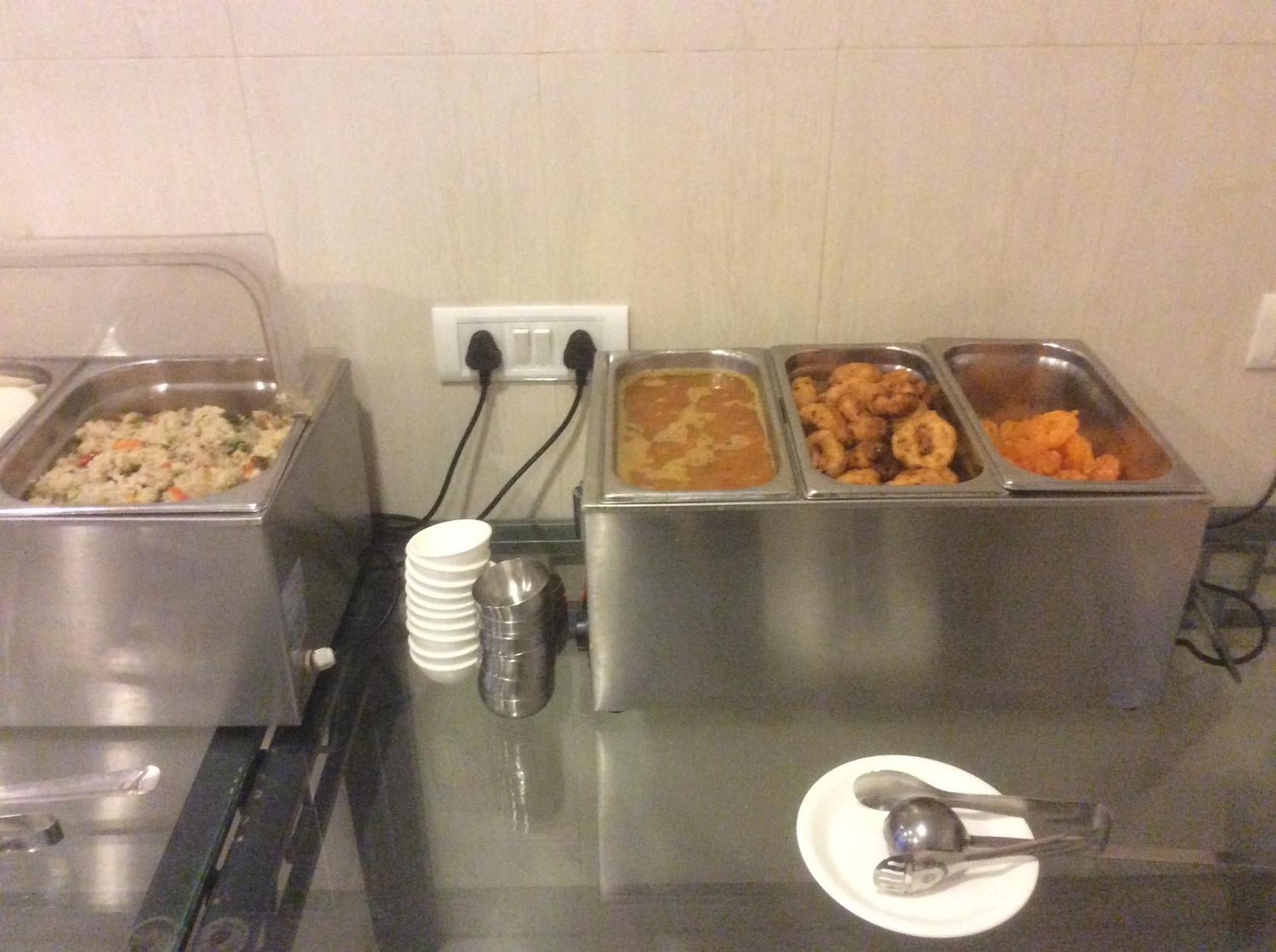 A buffet setup with various food containers and utensils.
