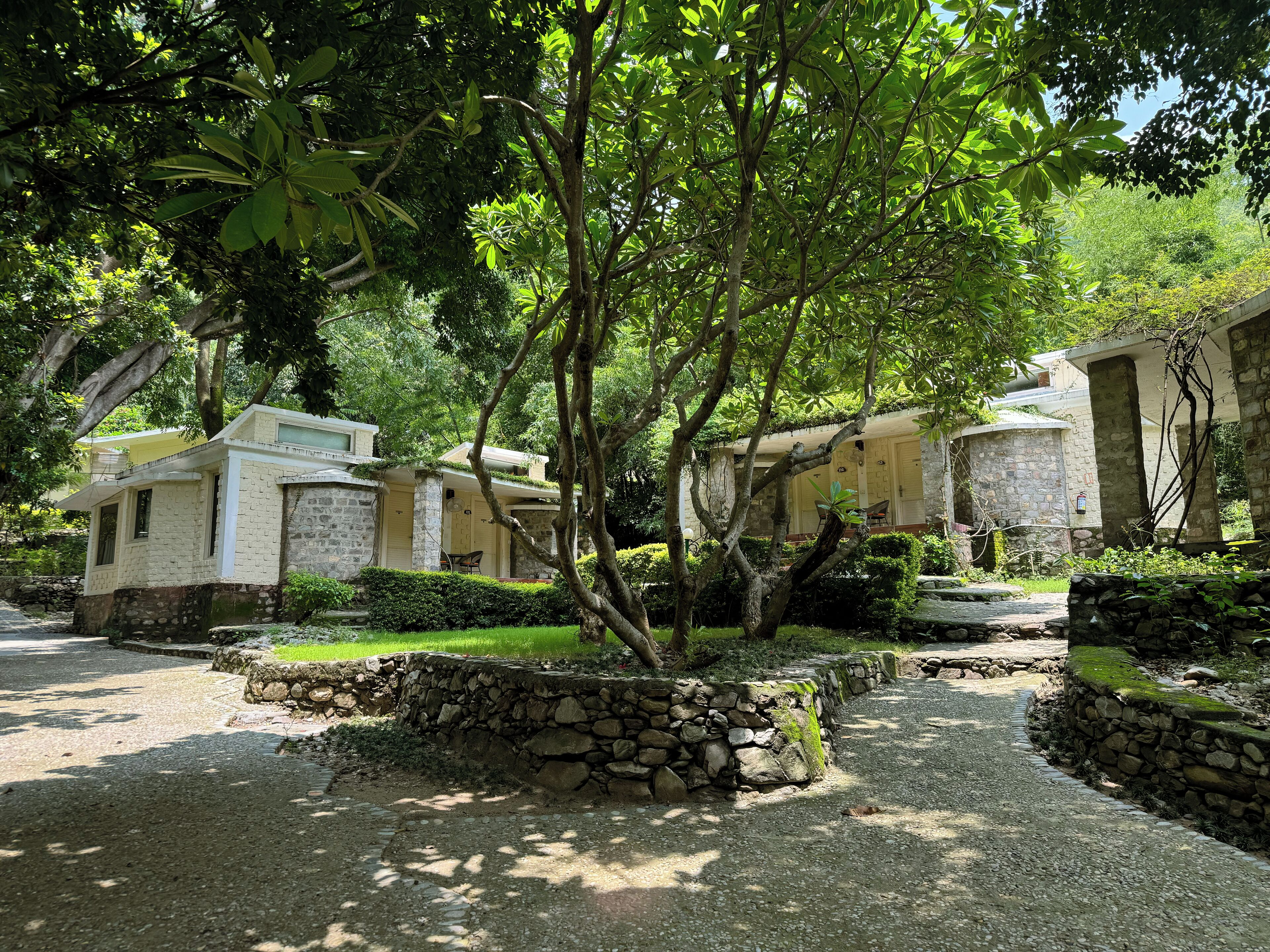 Un edificio de piedra con un jardín, rodeado de árboles.