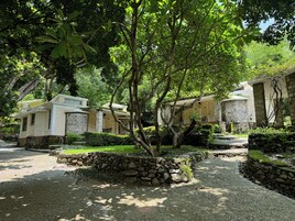 Un edificio de piedra con un jardín, rodeado de árboles.