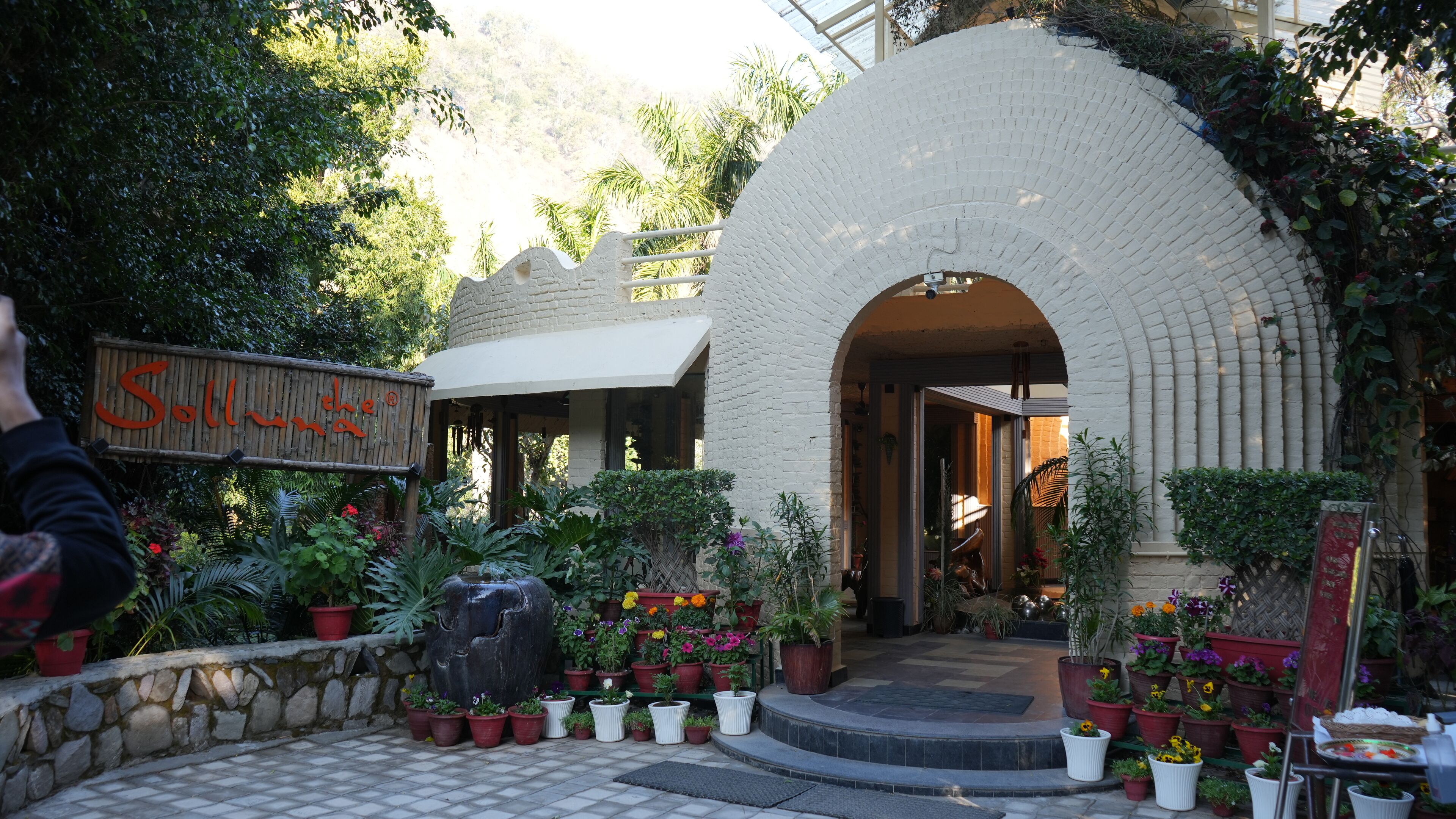 A courtyard with a stone wall, potted plants, and a sign reading "Solla".