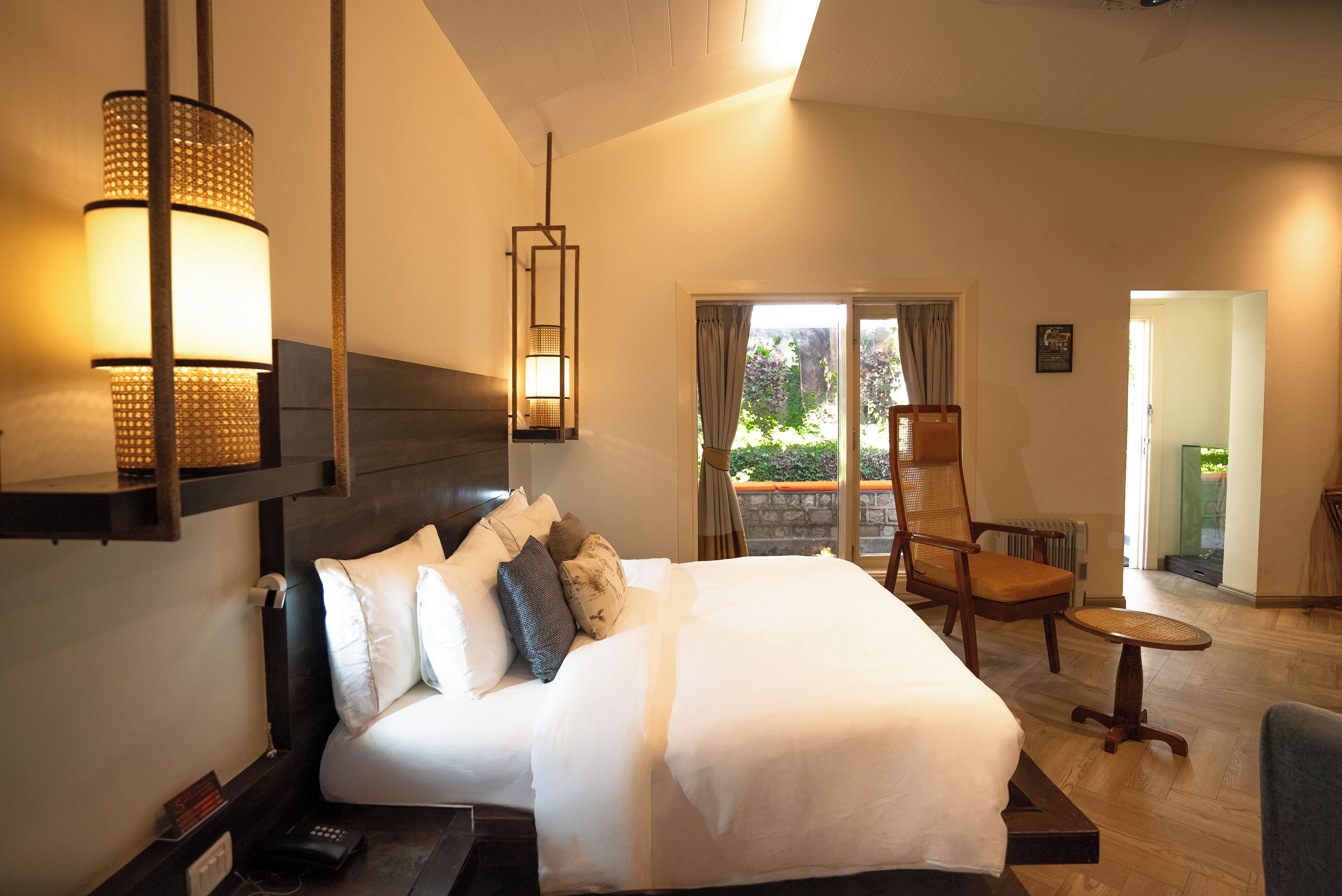 Una camera d'albergo ben illuminata con un letto grande, una sedia e un tavolino.