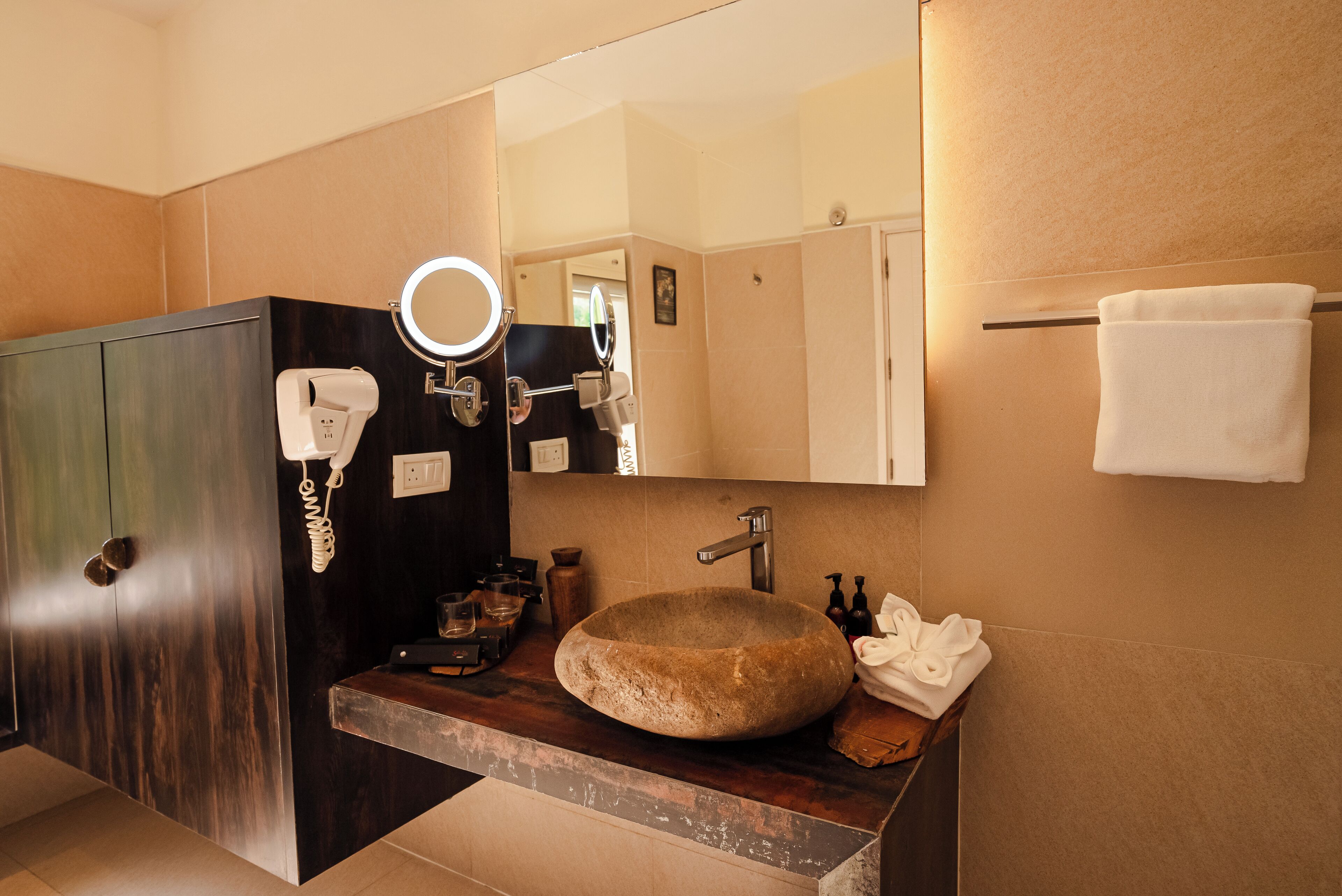 A bathroom with a stone sink, a mirror, a towel rack, and a cabinet.