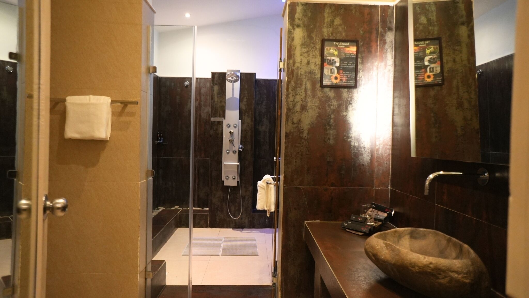 A modern bathroom with a glass-enclosed shower, a wooden vanity, and a stone basin.
