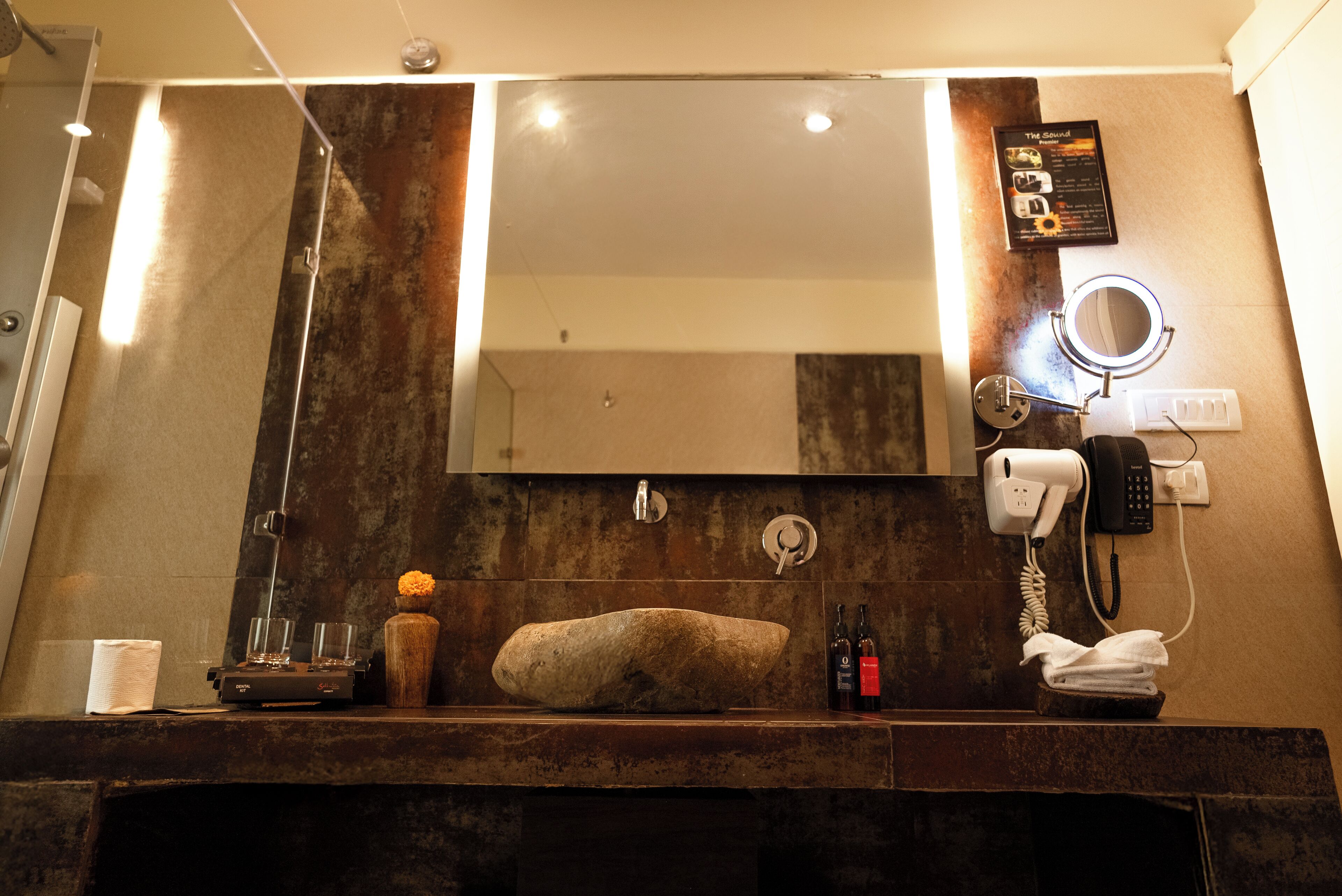 Un baño con un espejo grande, un lavabo, un secador de pelo y un perchero para toallas.