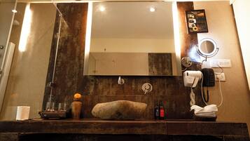 Un baño con un espejo grande, un lavabo, un secador de pelo y un perchero para toallas.