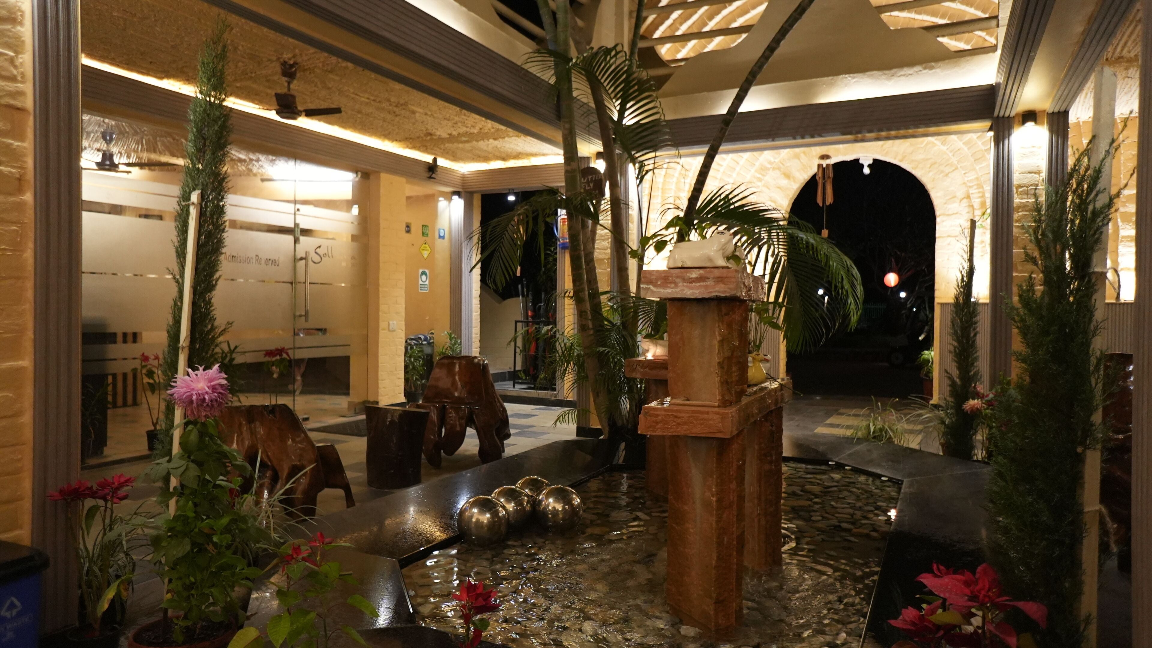 An indoor courtyard with a water feature, potted plants, and a stone pathway.