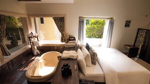 Une chambre d’hôtel moderne dotée d’une grande baignoire, d’un canapé-lit et d’un bureau avec un téléphone.