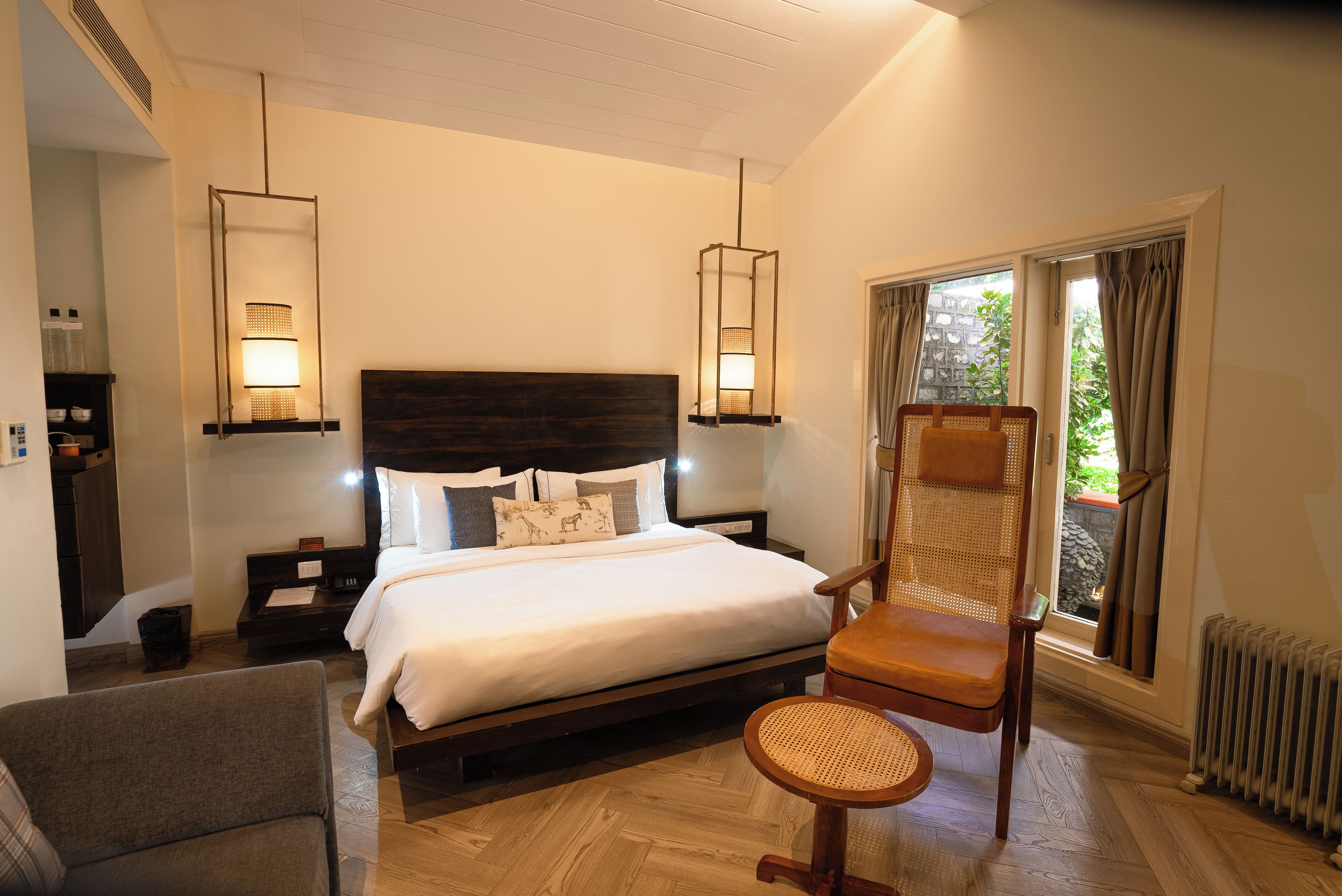 A hotel room with a large bed, a chair, a desk, and a window with curtains.