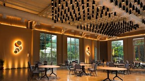 Un espace intérieur spacieux, doté de nombreuses tables et chaises, de grandes fenêtres et d’un plafond orné de luminaires suspendus.