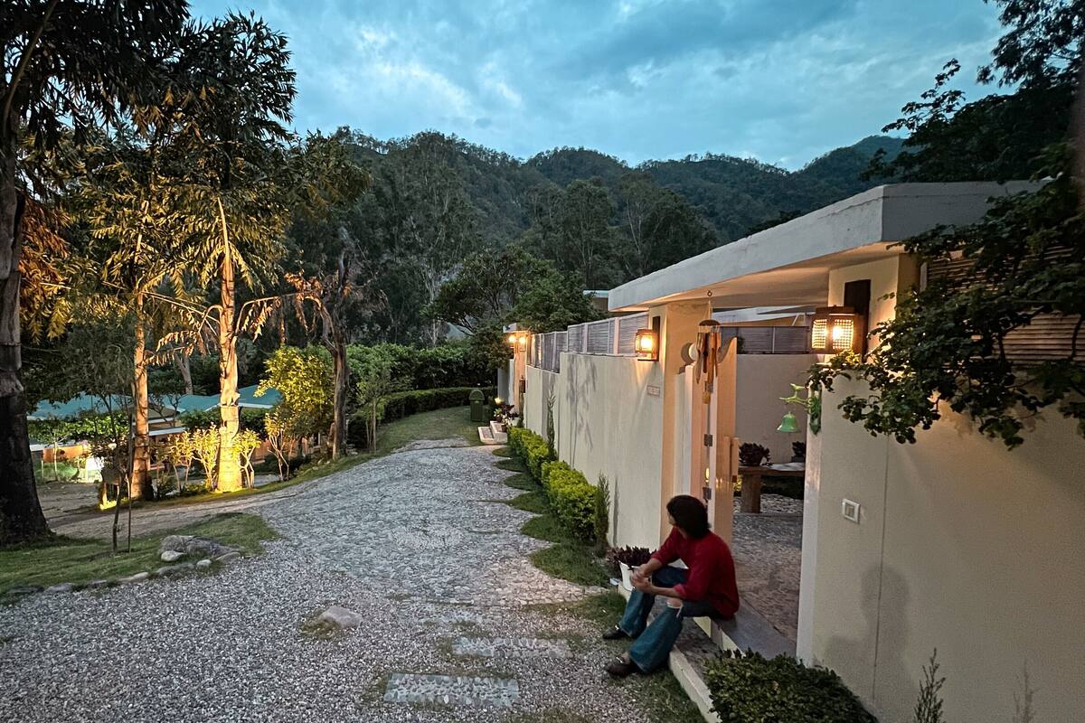 A pathway leading to a building with a person sitting on a bench.