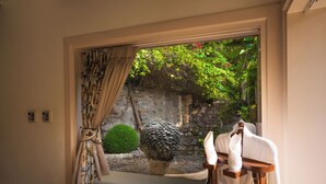 Une salle de bain avec une fenêtre, un porte-serviettes et un mur en pierre à l’extérieur.
