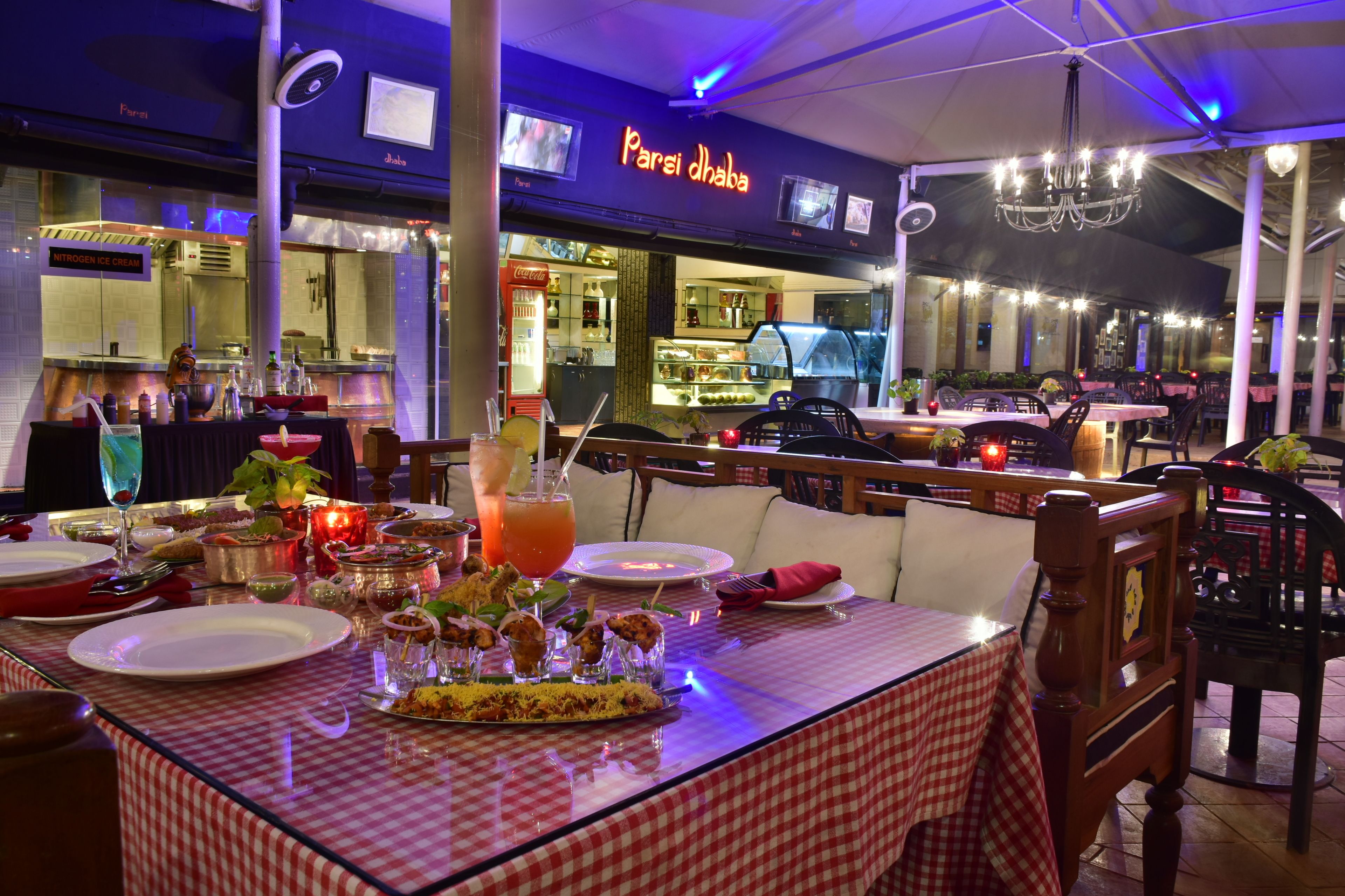 A restaurant with a checkered tablecloth, a neon sign, and a chandelier.
