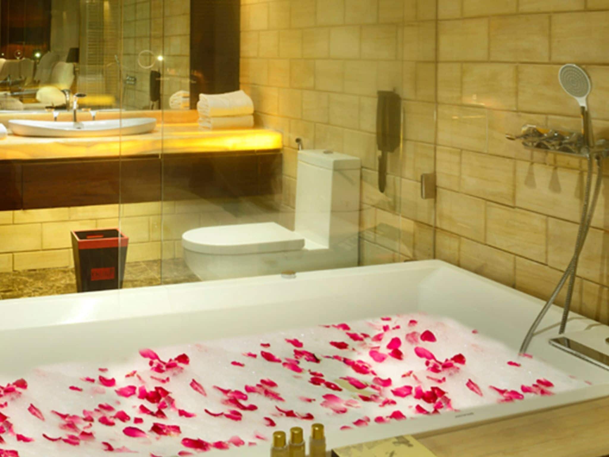 A bathroom with a bathtub filled with rose petals, a toilet, and a sink.