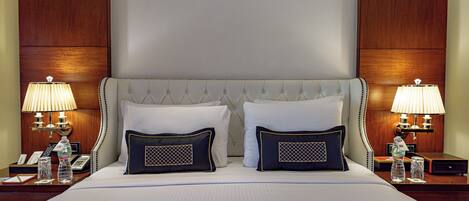 A hotel room with a large bed, two bedside tables with lamps, and a wooden headboard.