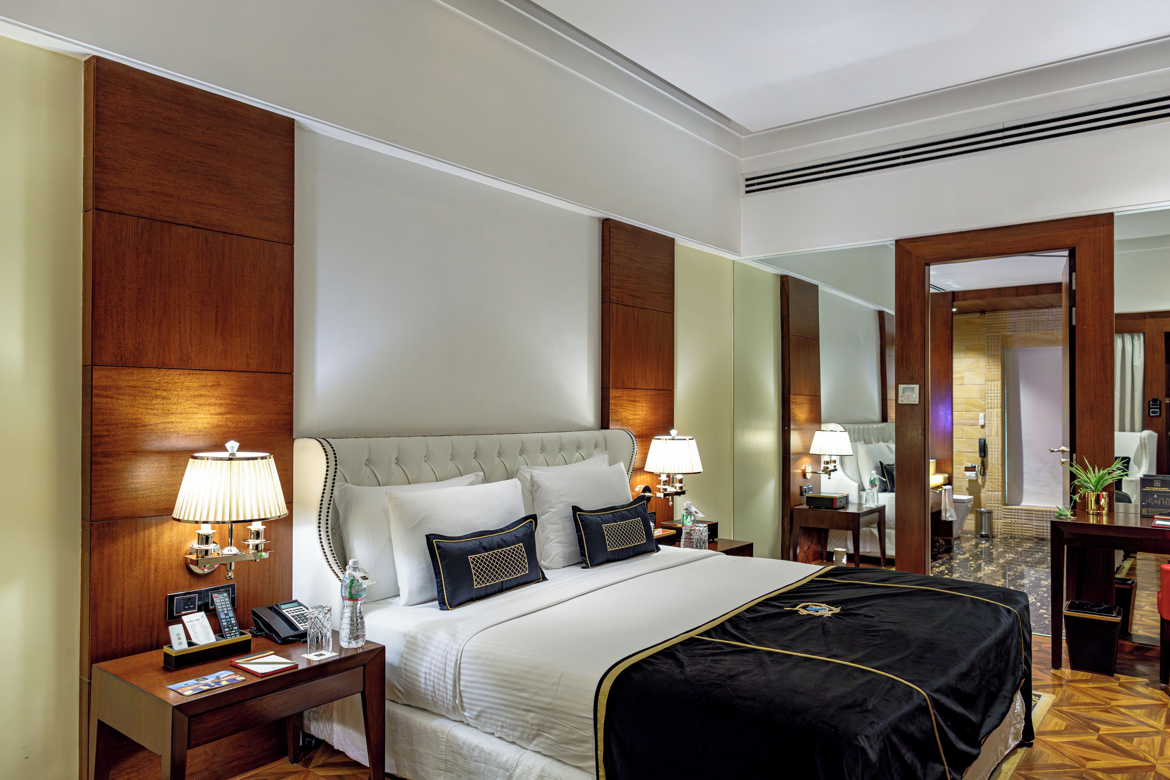 A hotel room with a large bed, two bedside tables with lamps, a desk, and a chair.