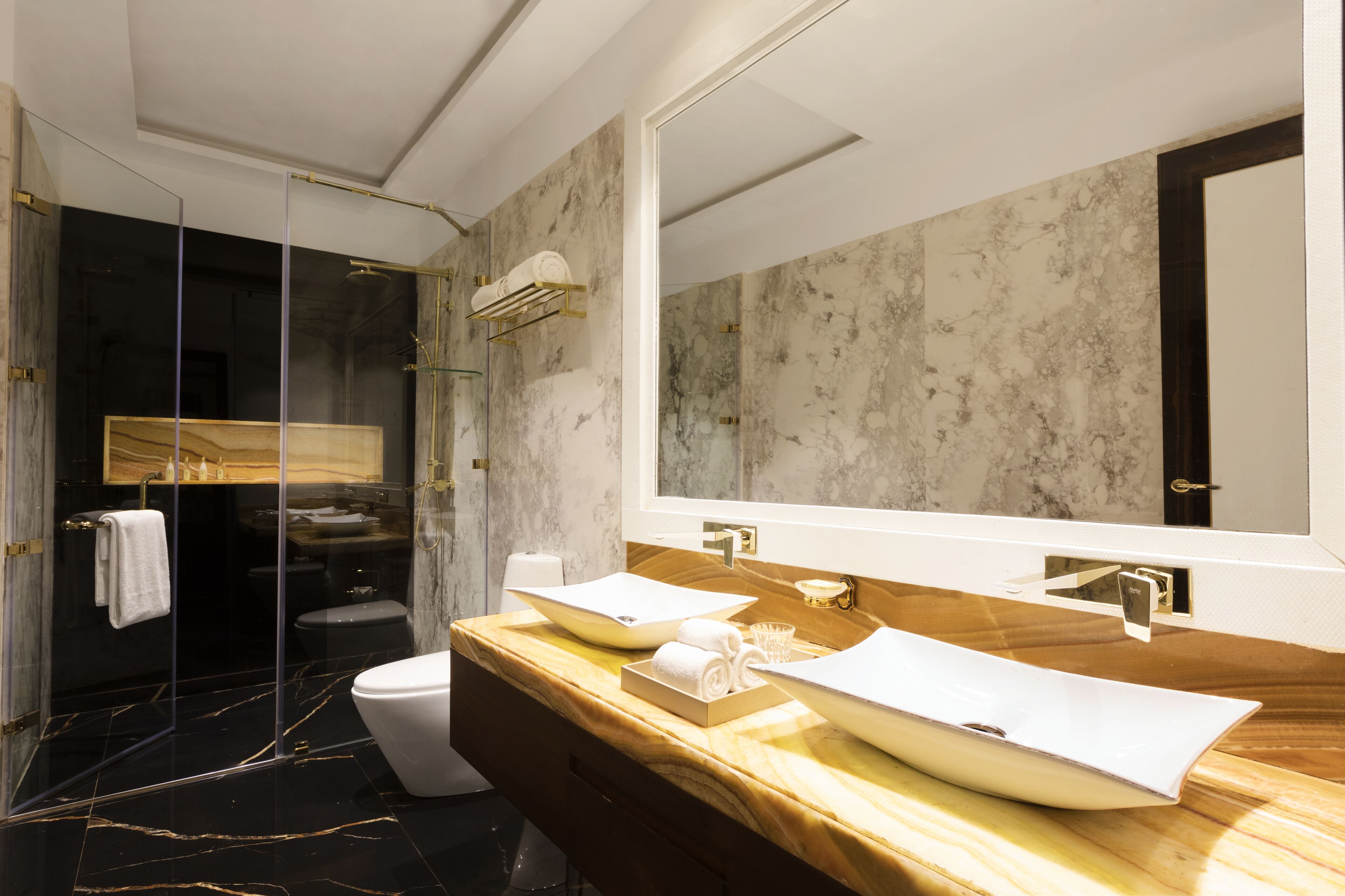 A modern bathroom with a large mirror, two sinks, and a glass-enclosed shower.