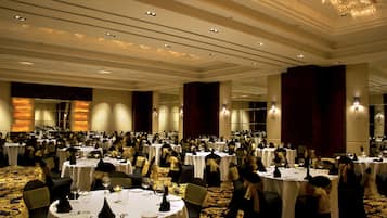 Un salón de banquetes con mesas redondas, sillas y suelo alfombrado.